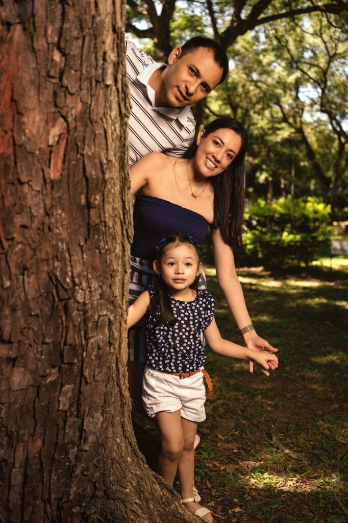 young latin family with girl, hiding behind a tree